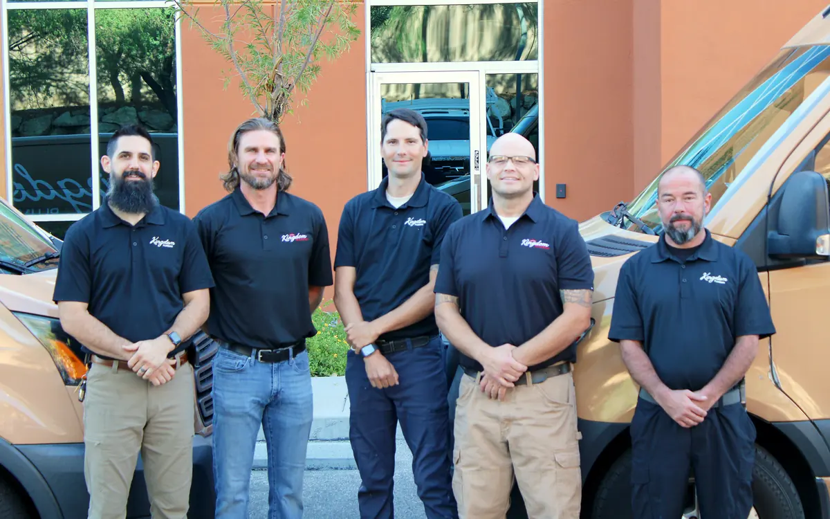 Kingdom Plumbing's Las Vegas plumbing team in uniform polos beside the company service vans