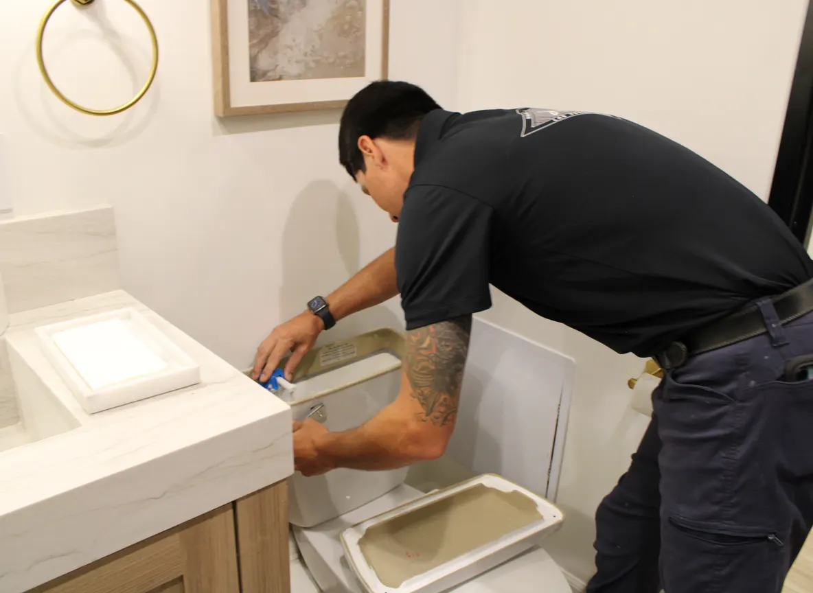 Plumber working inside an open toilet tank during a toilet repair in Las Vegas