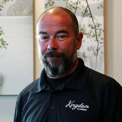 Kingdom Plumbing technician with a gray beard in a company polo at the Las Vegas office