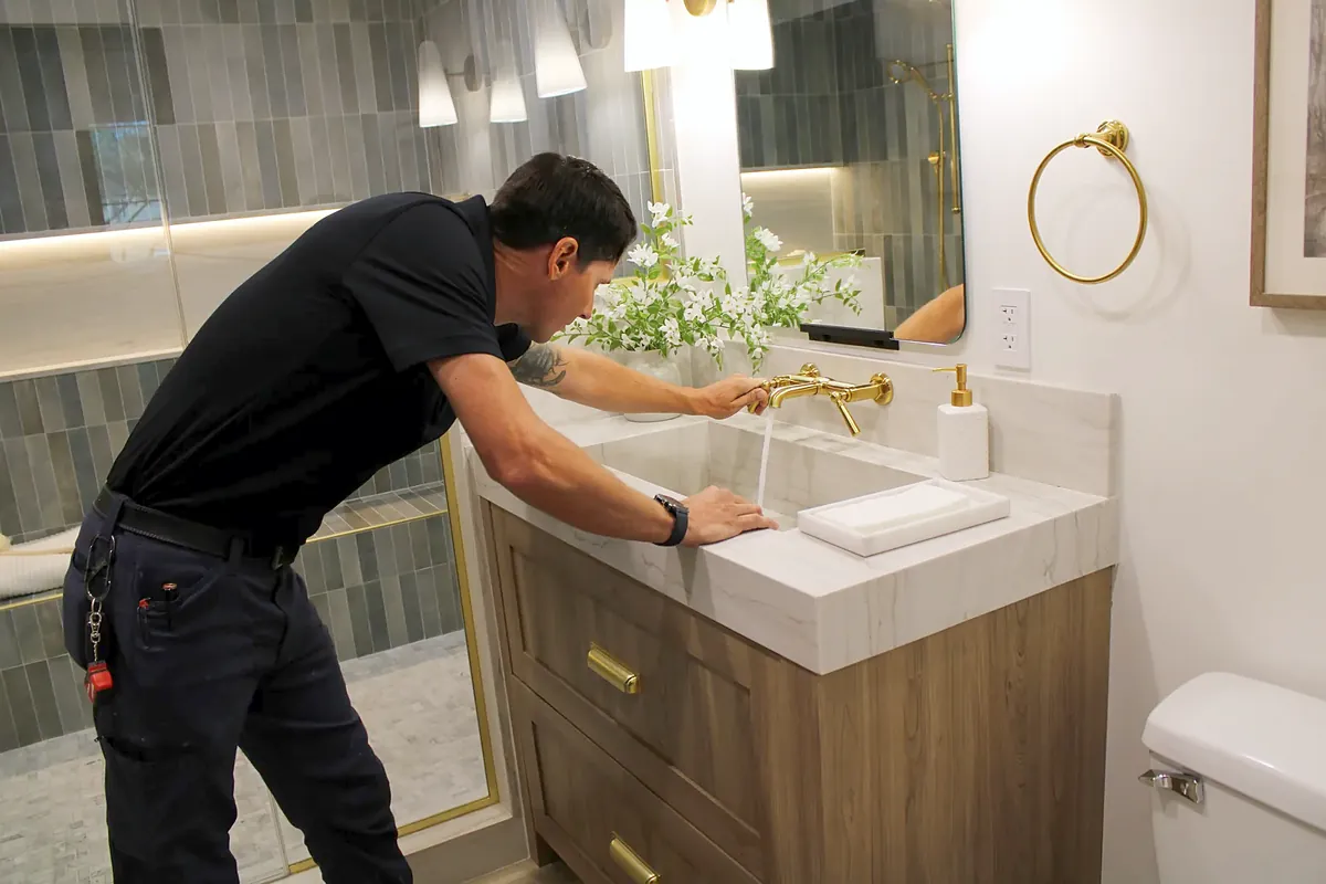 Technician testing water flow at a bathroom vanity faucet after a faucet repair